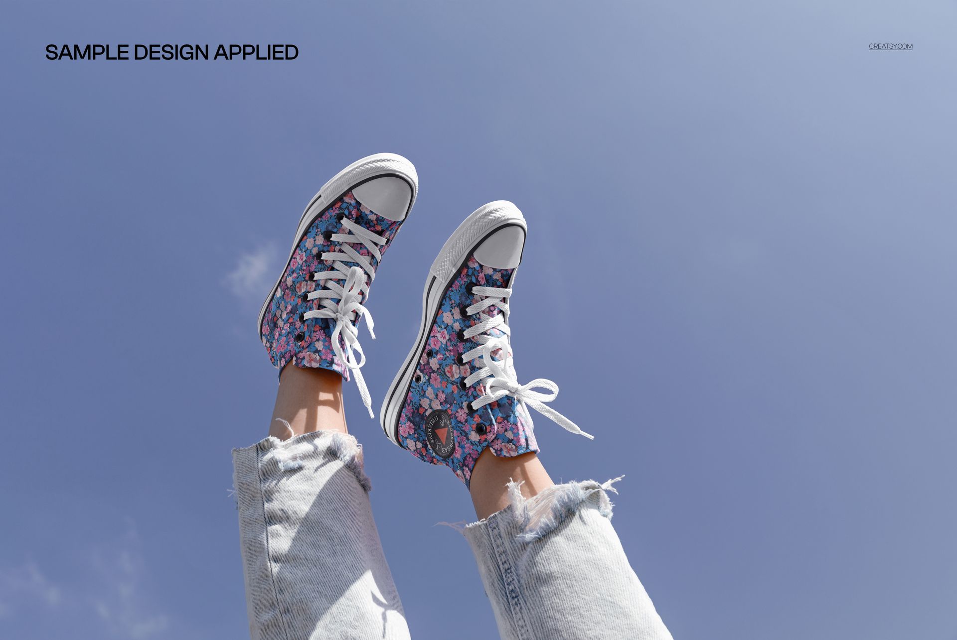 PSD mockup of floral high-top sneakers on feet, photographed from a low angle with sky and casual jeans visible.