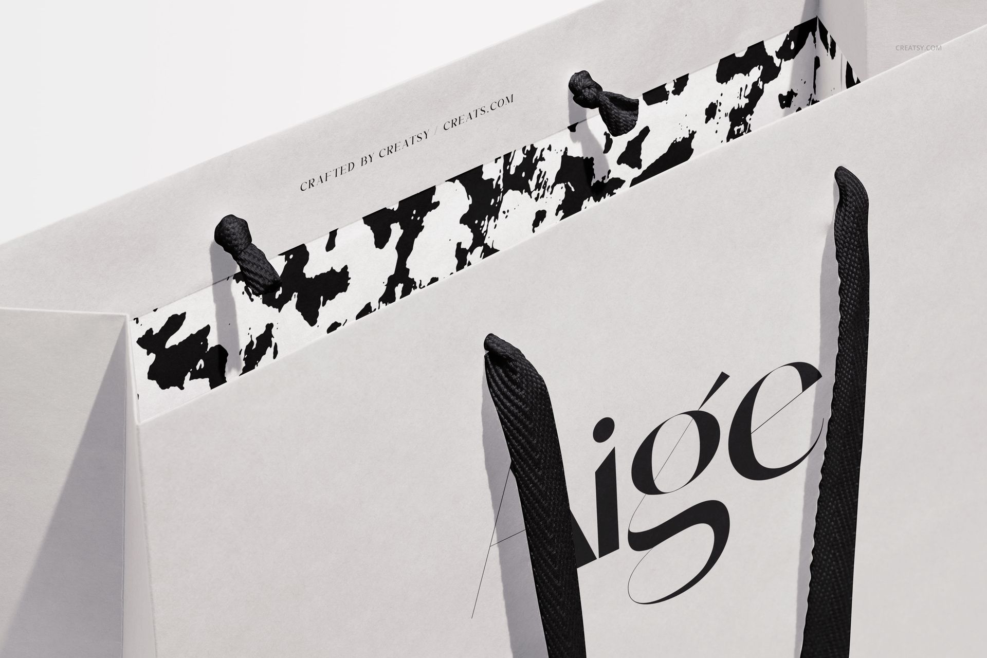 Close-up of a paper gift bag mockup with black ribbon handles and a striking monochrome interior design.