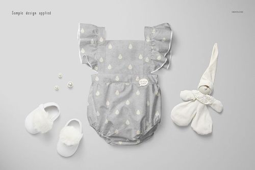 Gray baby romper mockup with white drop shapes, flanked by soft baby shoes, plush toy, and small pearls on a light background.