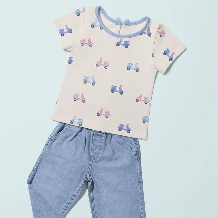 Kids t-shirt and jeans mockup featuring a cream shirt with colorful scooter illustrations, laid flat on a light blue background.