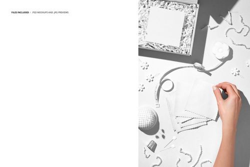 PSD mockup showing jersey fabric samples, a hand, box with shredded paper, and sewing tools arranged on a light surface.