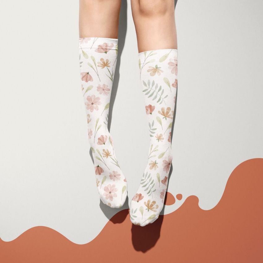 Sublimation tube socks mockup featuring a pair of legs wearing white socks with a pastel floral pattern on a minimal background.