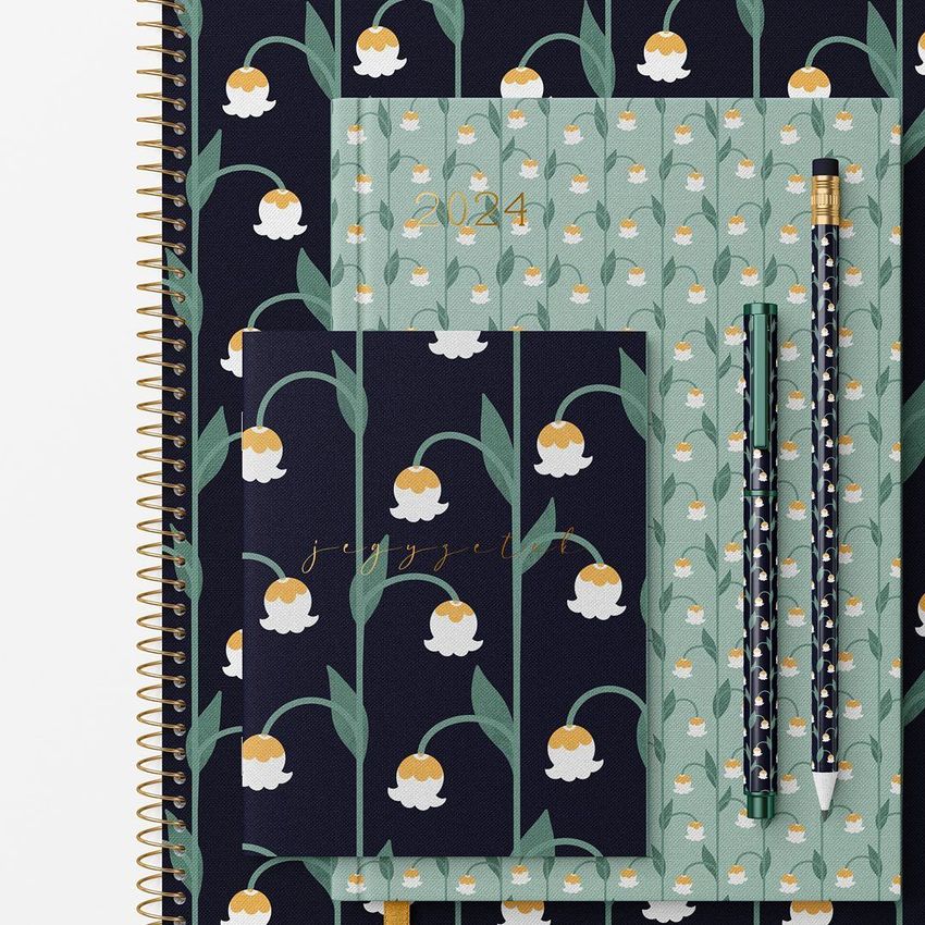 Stationery set mockup featuring notebooks and pencils with lily of the valley patterns in dark and pastel green tones, viewed from above.