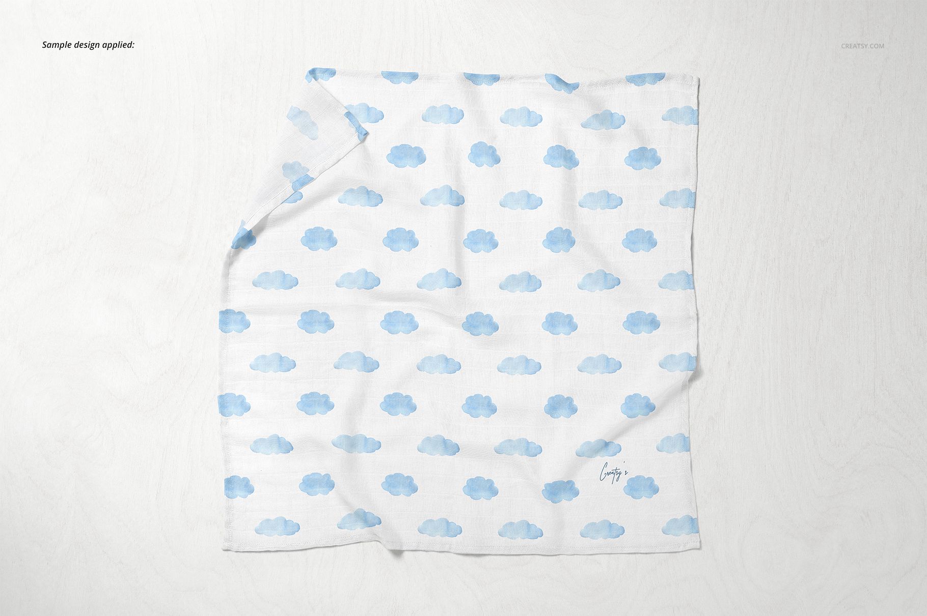 Baby muslin square nappy mockup featuring a soft white fabric with blue clouds, shown from above on a pale background.