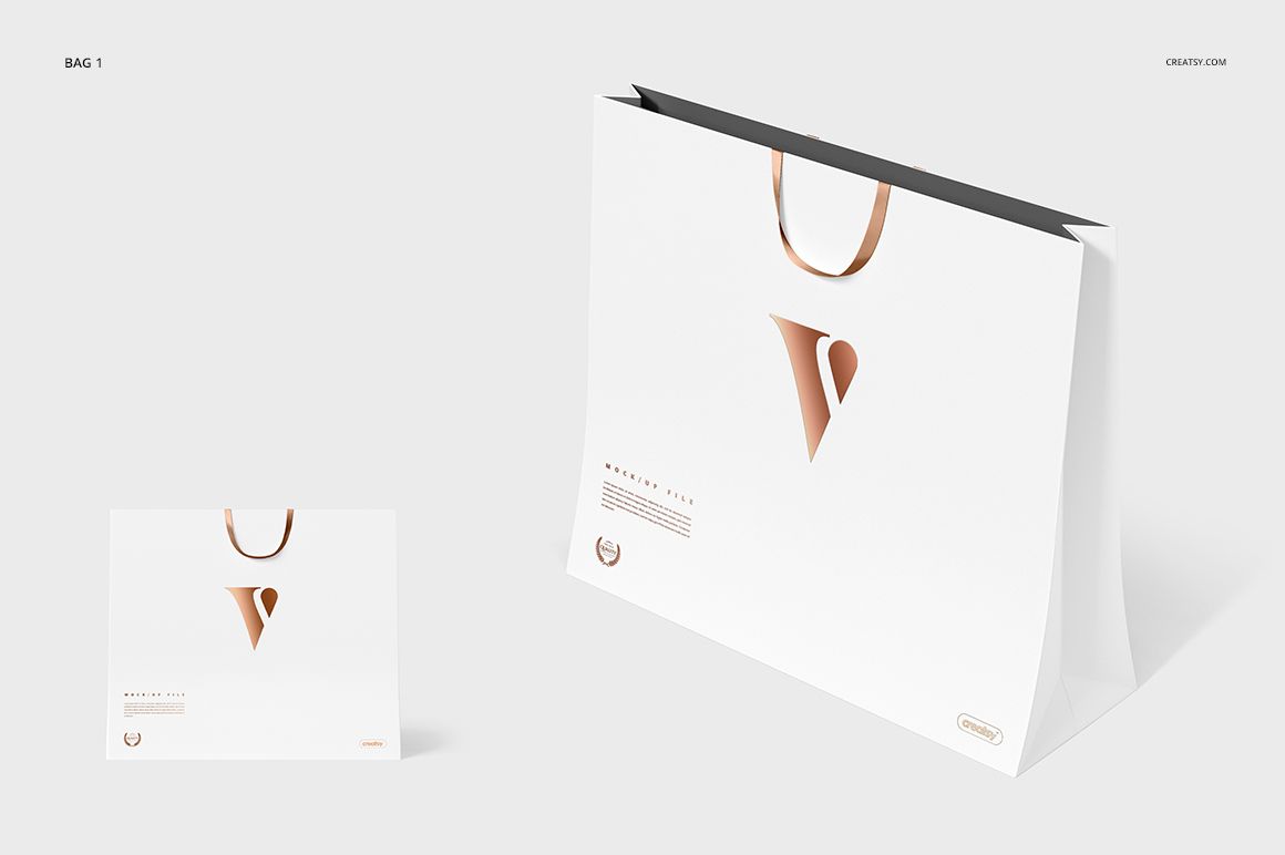 White gift bag mockup featuring a gold handle and simple gold emblem, shown from the front on a plain surface.