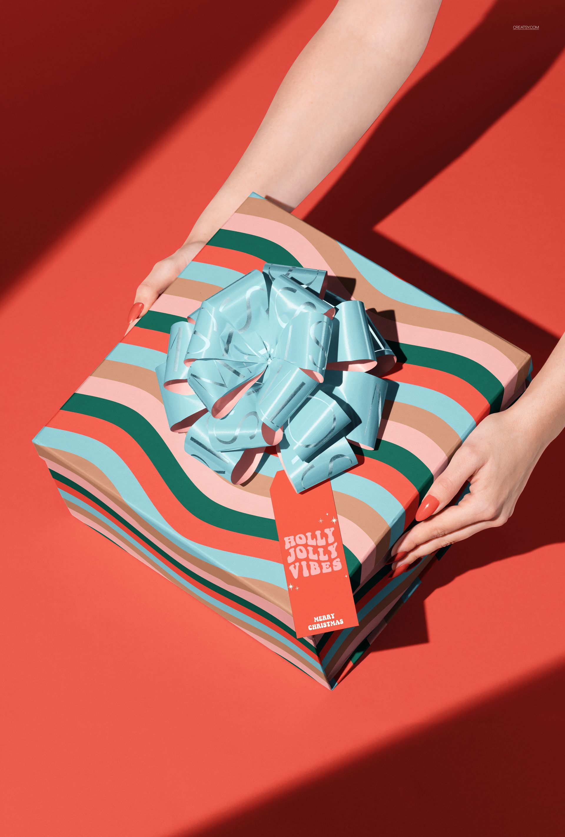 PSD mockup of a holiday gift box featuring multicolored wavy stripes, a large blue ribbon, and a red background.