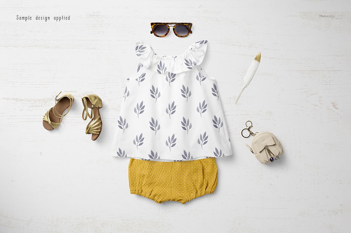 Baby summer set mockup featuring a white top with gray leaf pattern and mustard yellow shorts, flat lay on white wood.