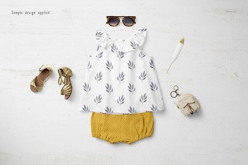 Baby summer set mockup featuring a white top with gray leaf pattern and mustard yellow shorts, flat lay on white wood.
