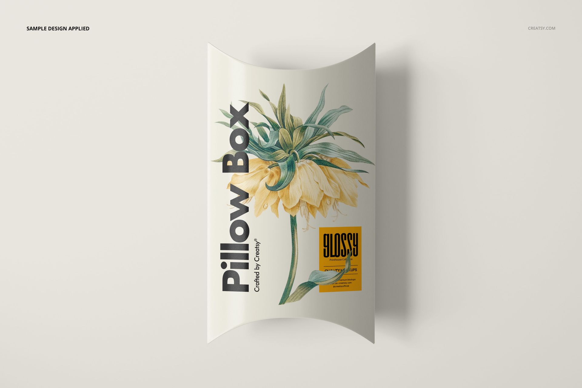 Top view of a rectangular pillow box mockup featuring a yellow flower design and bold black lettering.