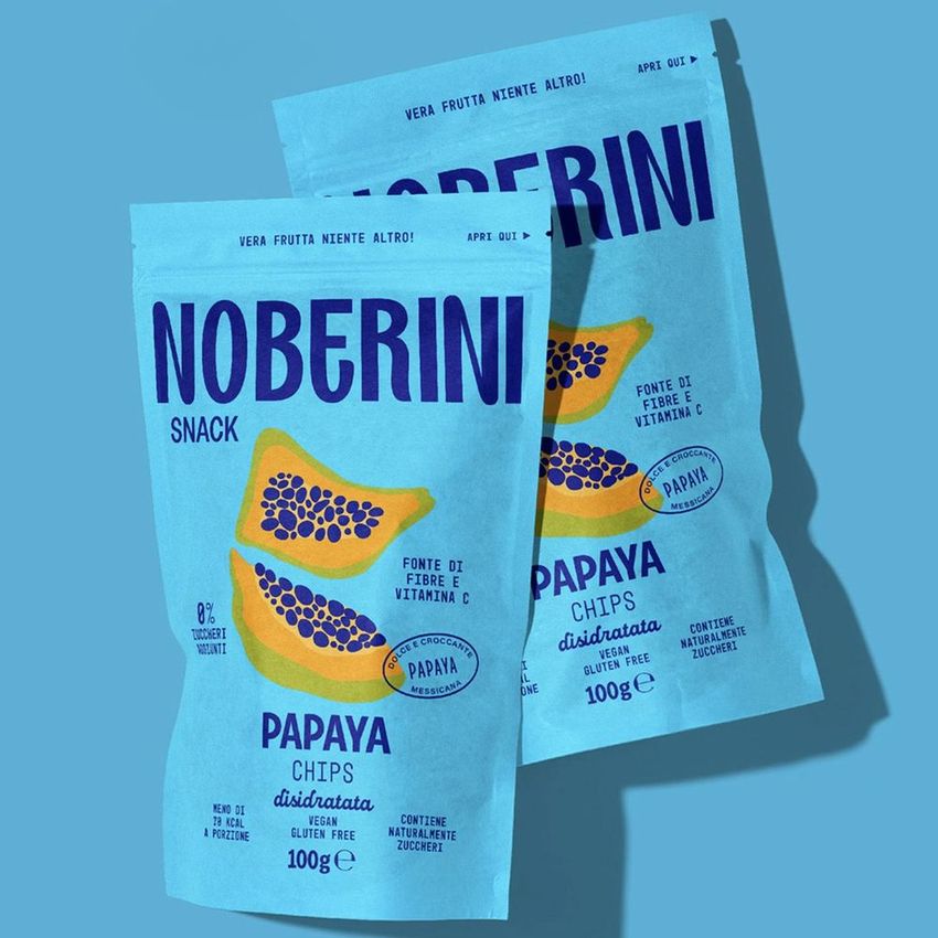 Stand up paper pouch mockup featuring two blue snack bags with papaya illustrations and bold text, set on a matching blue background.