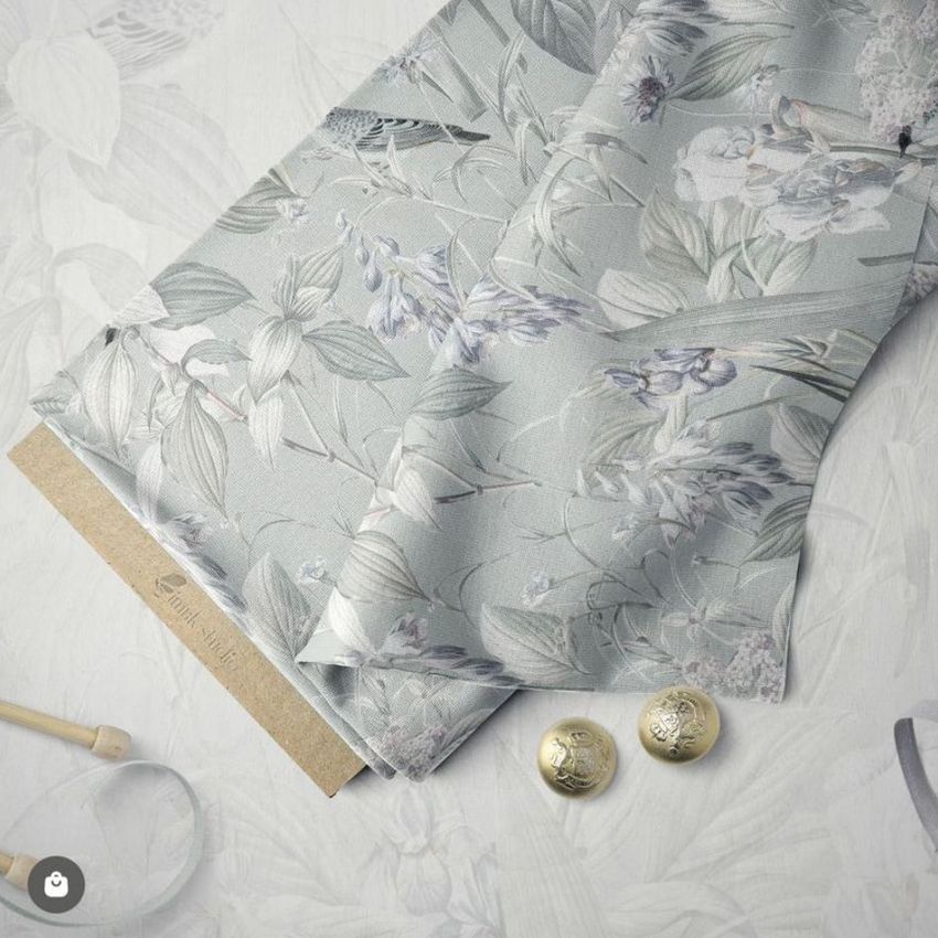 Fabric bolt mockup featuring a close-up of floral patterned fabric in muted tones, with ribbons and gold buttons on a light background.