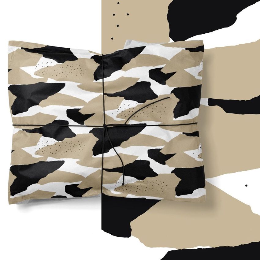 Tissue paper mockup featuring two wrapped packages with abstract black, beige, and white patterns on a matching background.