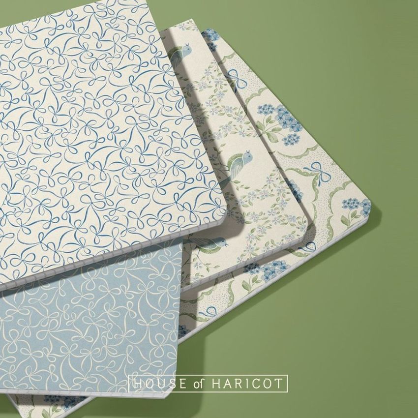 Group of four notebook mockup featuring covers with blue and green floral and bow patterns, arranged on a green background.