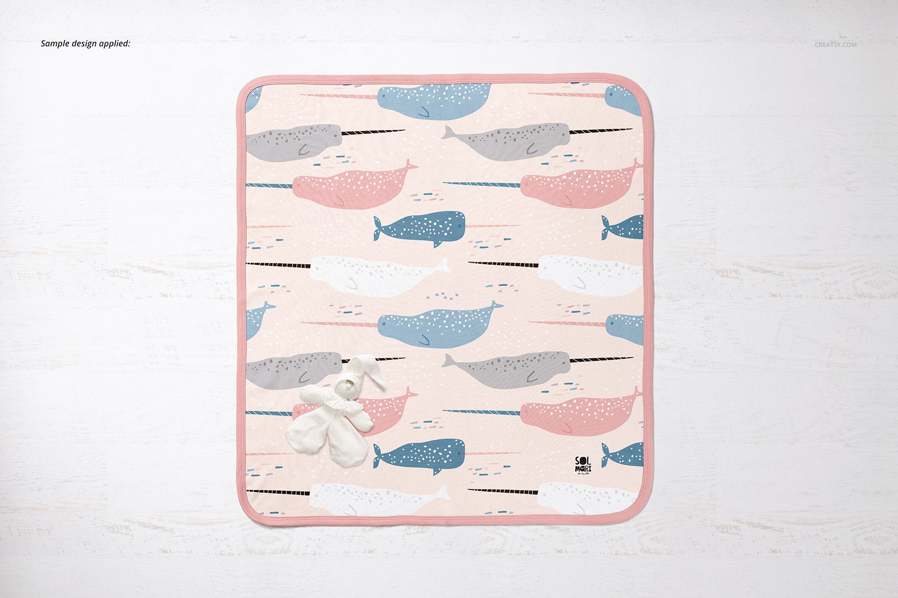 Top view of a cotton baby blanket mockup with pastel whale design and plush toy, displayed on a light background.