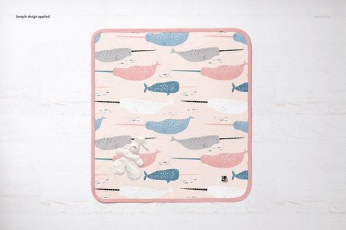 Top view of a cotton baby blanket mockup with pastel whale design and plush toy, displayed on a light background.