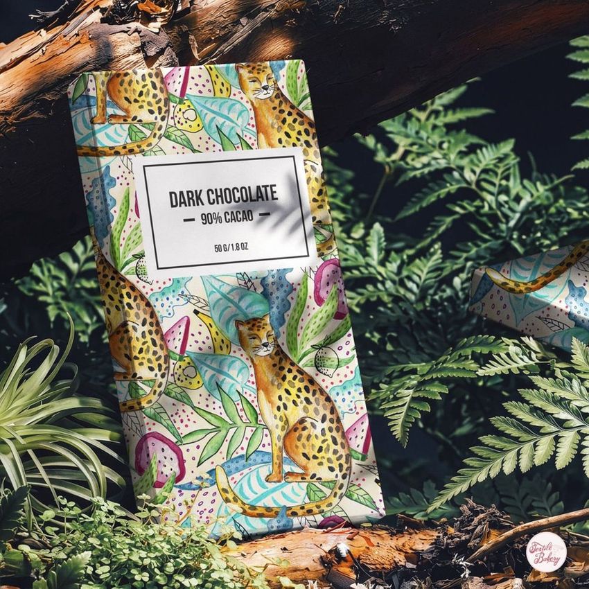 Chocolate box mockup featuring a colorful illustrated cheetah and tropical leaves, placed on forest branches with greenery.