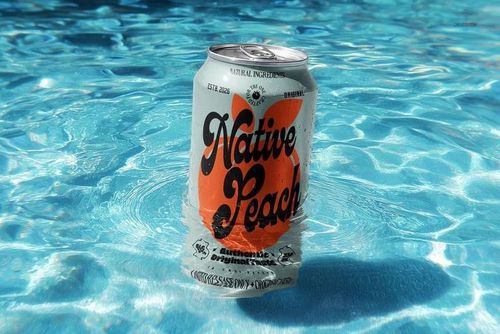 Silver drink can with orange and black design floating upright in clear blue water, front view, realistic mockup.