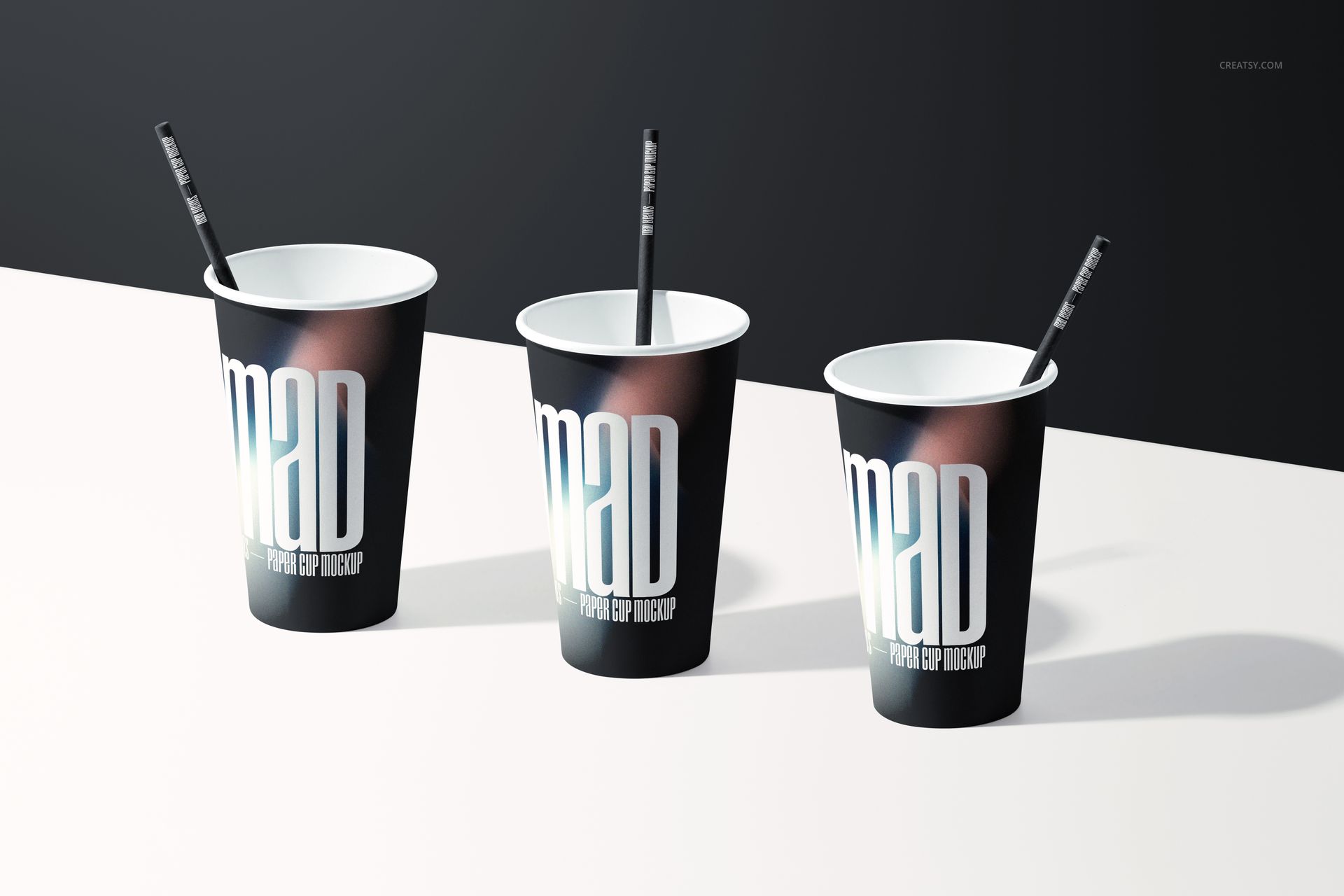 PSD mockup showing a trio of paper cups with dark designs and straws, positioned side by side on a light background.