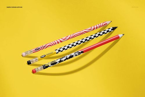 Abstract presentation of three pencils mockup featuring unique designs on a yellow surface, viewed from above.