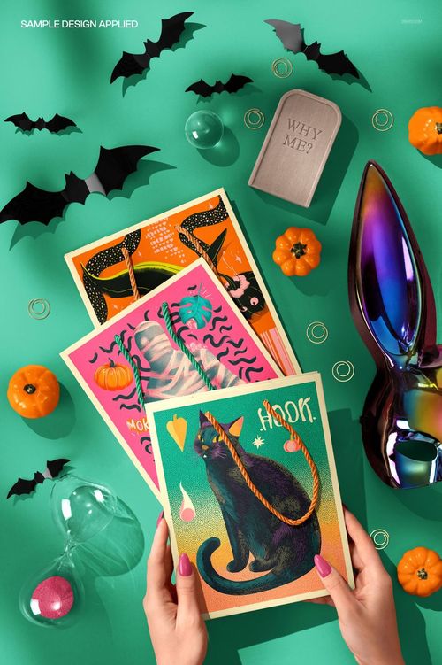 Halloween paper gift bag mockup featuring vibrant prints, mini pumpkins, black bat decorations, and a metallic bunny figurine.