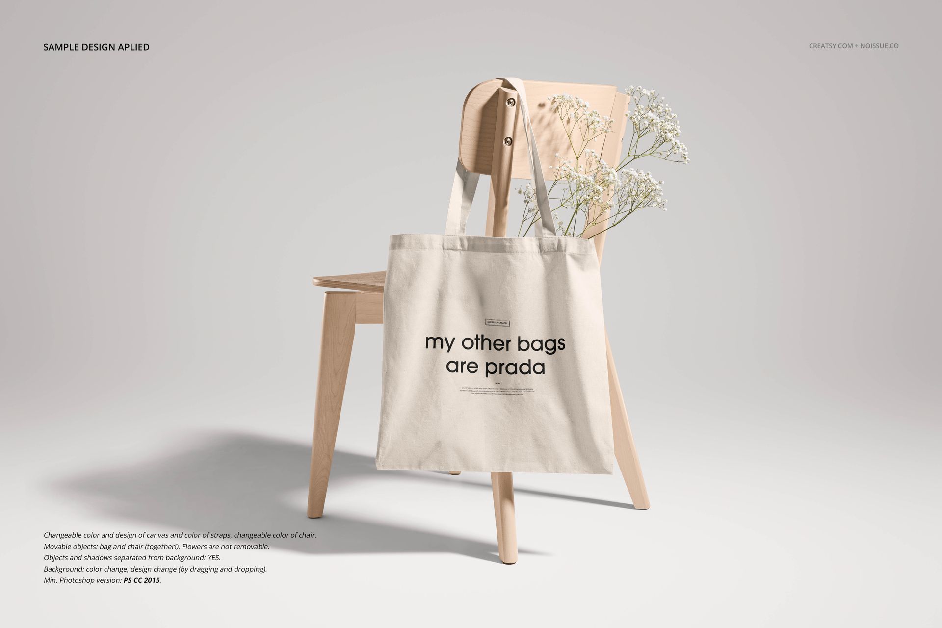 Mockup of a natural canvas tote bag with printed text displayed on a wooden chair, white flowers as props.