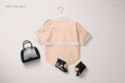 Front view of a baby coat mockup in light peach with white dots, displayed on a hanger with black shoes and a handbag.