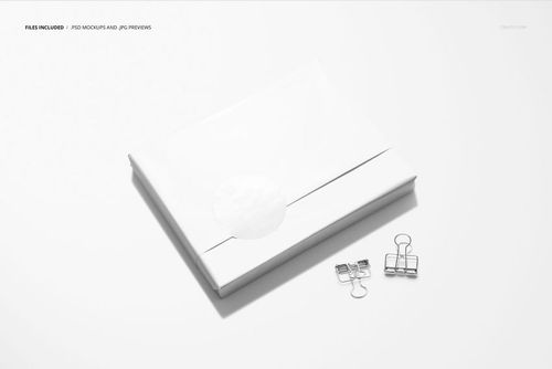 Book in white wrapping paper mockup, shown from above with metal binder clips on a minimal white background.