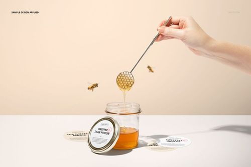 Front view of honey jar with metal lid, custom round sticker mockup, honey dipper and bees in minimal scene.