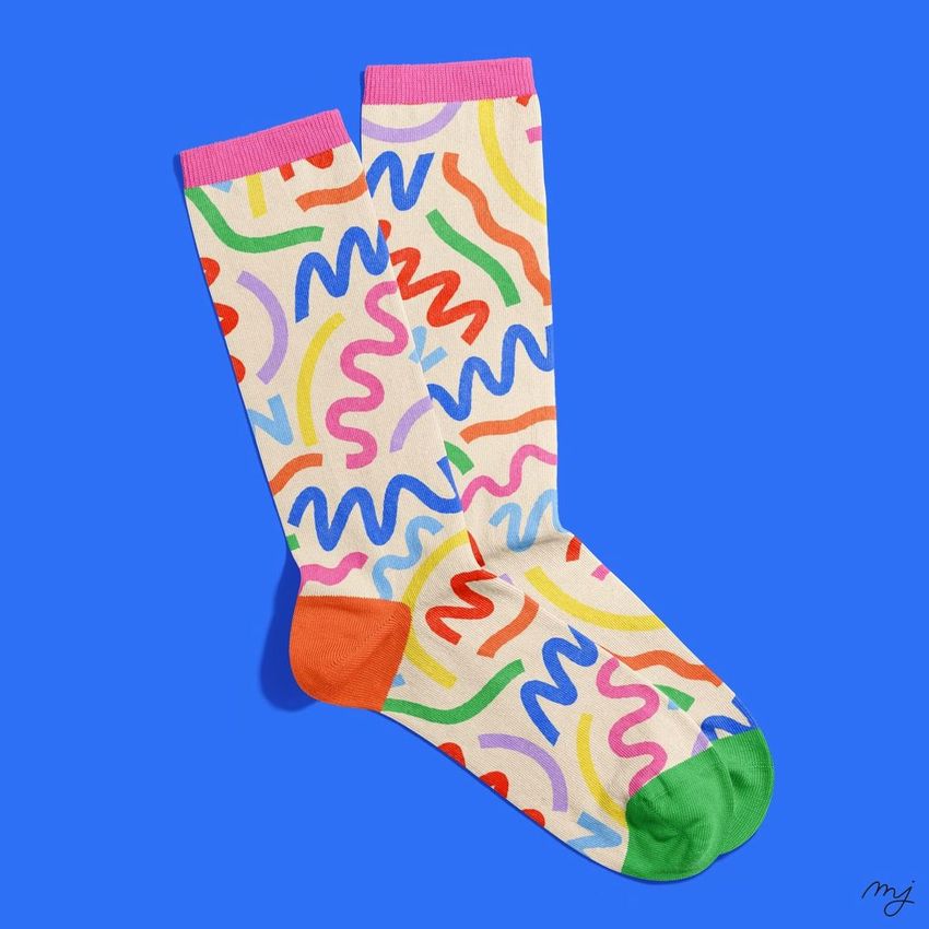 Socks mockup featuring a pair of white socks with colorful abstract squiggle patterns, orange and green toes, on a blue background.