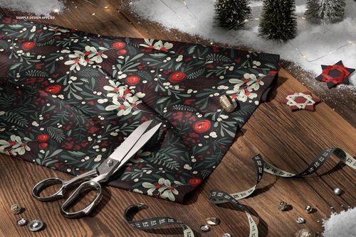 Winter-themed jersey fabric mockup featuring red berries and green leaves, shown from a top view with craft supplies nearby.