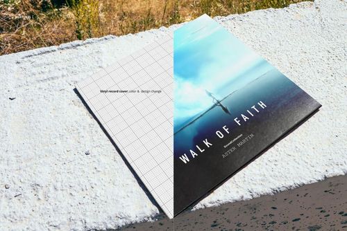 Vinyl record cover mockup displayed on a textured concrete surface near the seashore, with grass in the background.