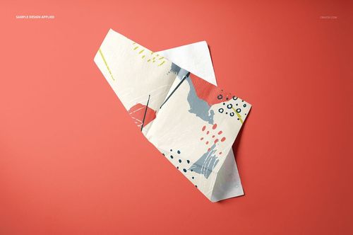 Paper napkins mockup featuring overlapping napkins with modern abstract designs on a solid coral surface.