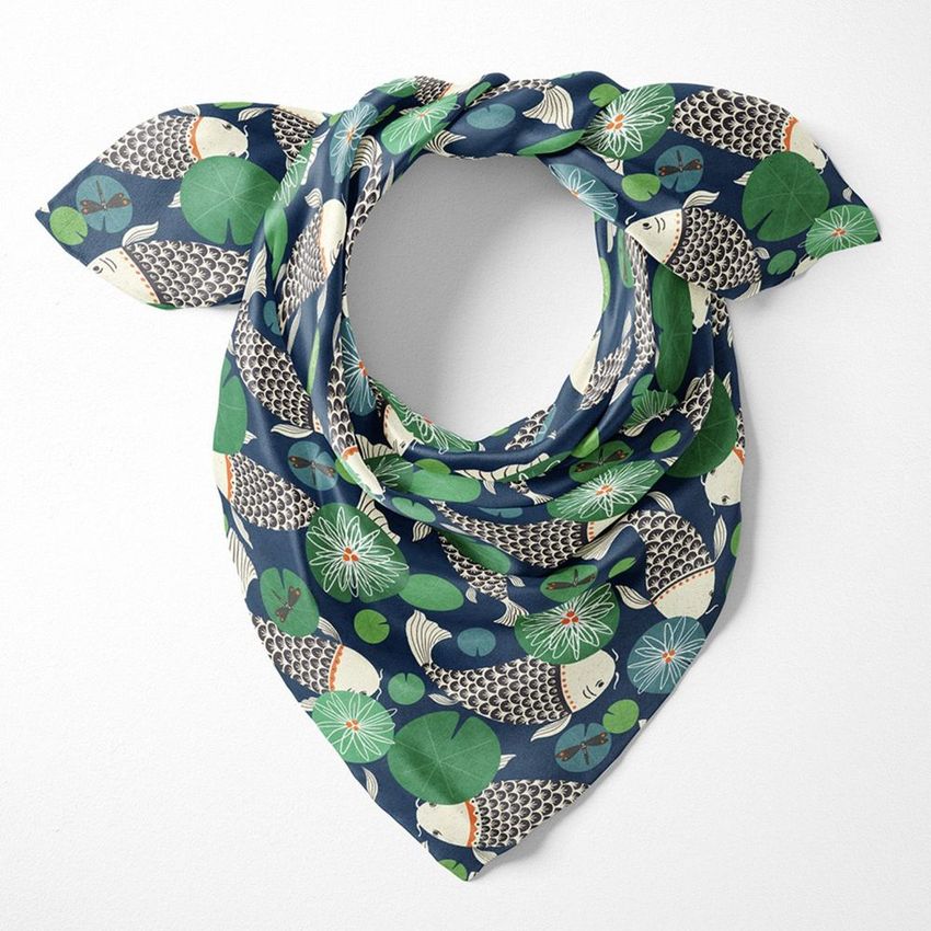 Silk scarf mockup displayed flat against a white background, featuring koi carp and lily pad illustrations in blue and green tones.