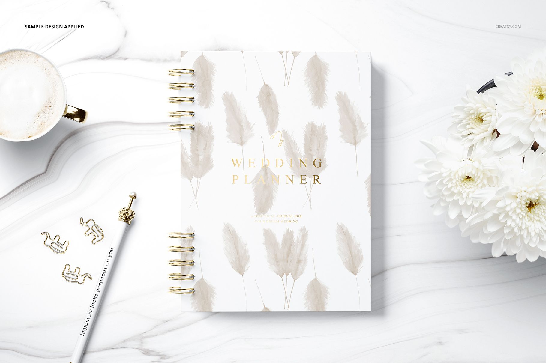 Spiral planner mockup on a white marble background, featuring soft beige leaf illustrations and gold text on the cover.