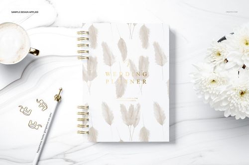Spiral planner mockup on a white marble background, featuring soft beige leaf illustrations and gold text on the cover.