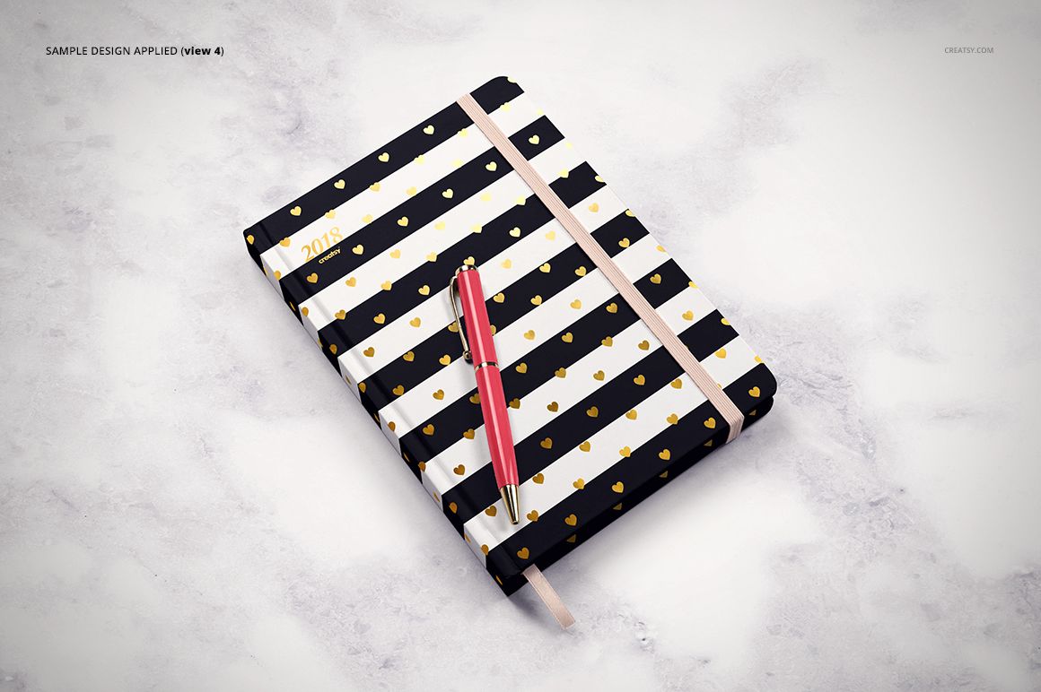 Striped planner mockup with gold accents and elastic band, displayed on a light marble background with a red pen.