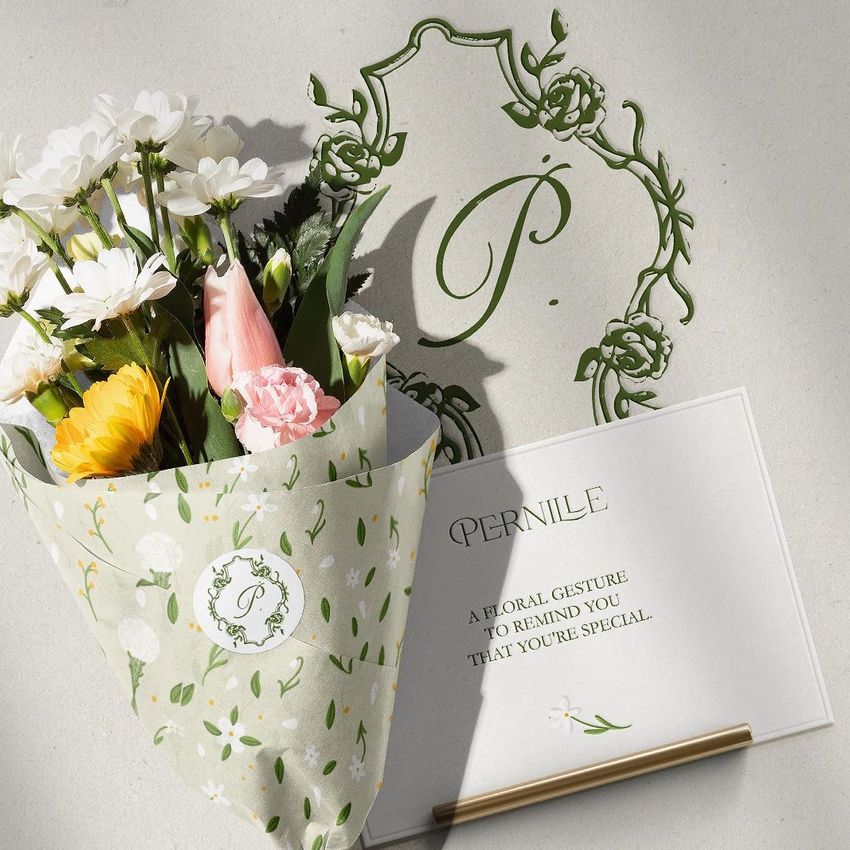 Flowers packaging mockup featuring a bouquet of mixed flowers wrapped in patterned paper beside a card with decorative text.