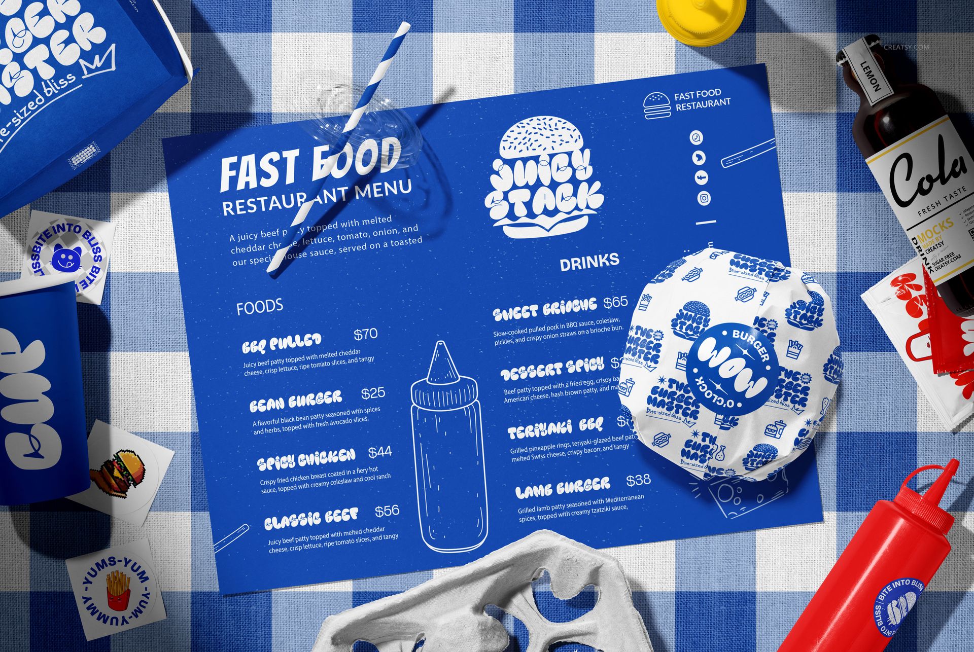 Vegan burger bar packaging mockup with branded wrappers, menu, drink cup, and cola bottle on a blue checkered table.