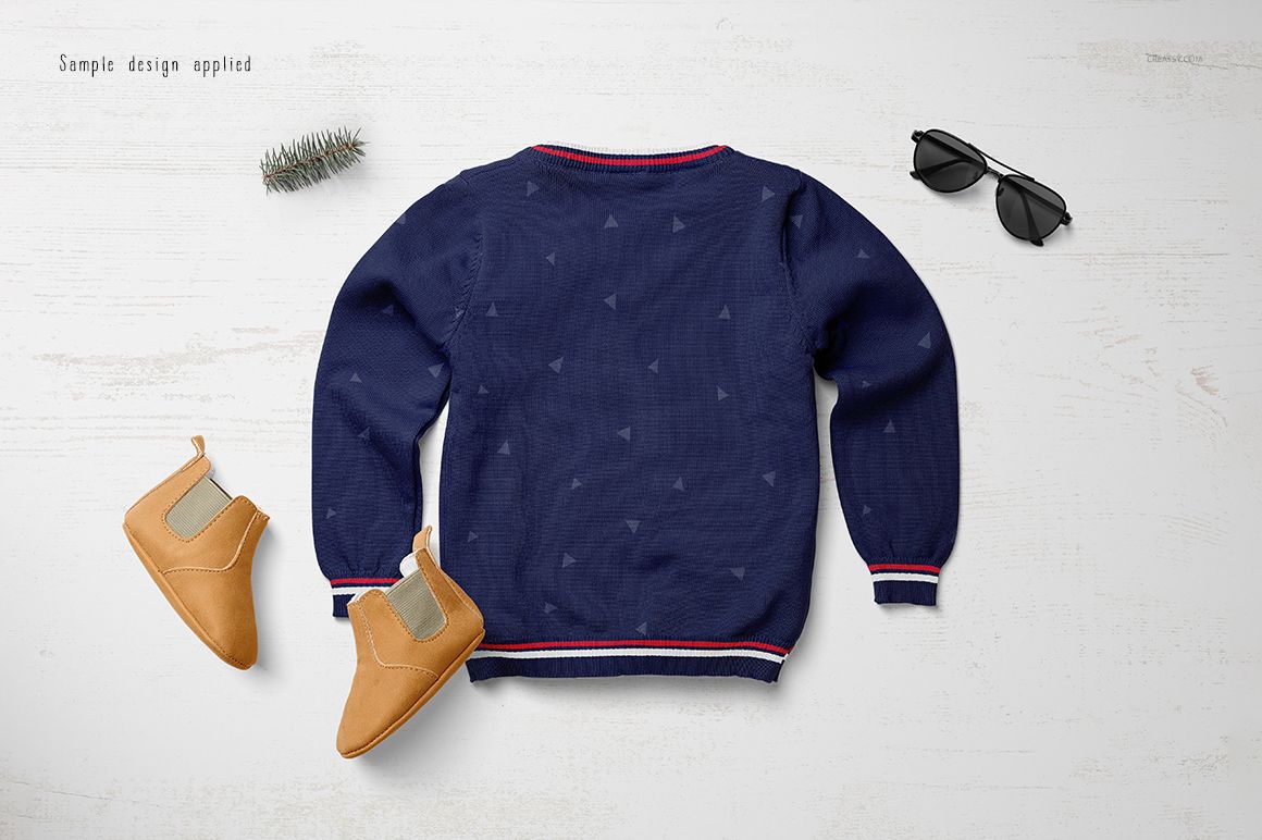 Boys sweater mockup in dark blue with small geometric shapes, displayed flat alongside tan shoes and black sunglasses.