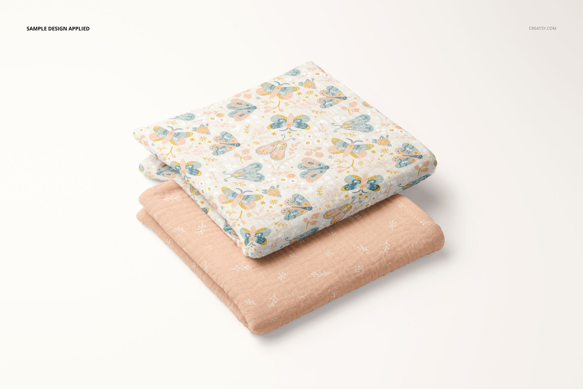 PSD mockup of two kids' muslin swaddle blankets, displayed folded, showing one patterned and one plain peach blanket.