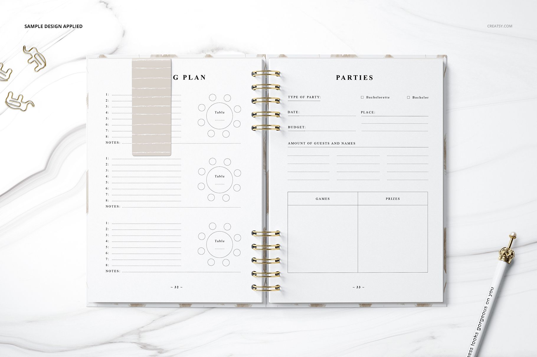Top view of an open planner mockup showing organized tables, guest lists, and a gold pen on a white marble background.