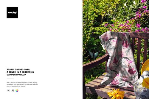 PSD mockup showing a piece of fabric with botanical print arranged on a garden bench amid lush greenery and blossoms.