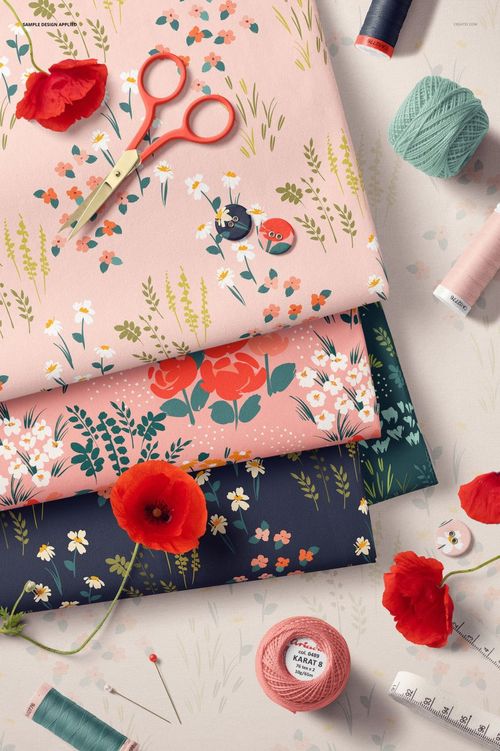 PSD mockup showing floral jersey fabrics in pastel and dark colors, with scissors, thread, and decorative flowers nearby.