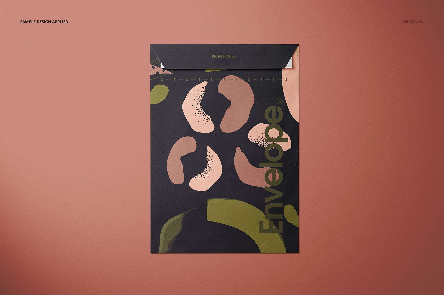 Front view of a square envelope mockup with abstract green and pink patterns on a dark background, set on a brown surface.