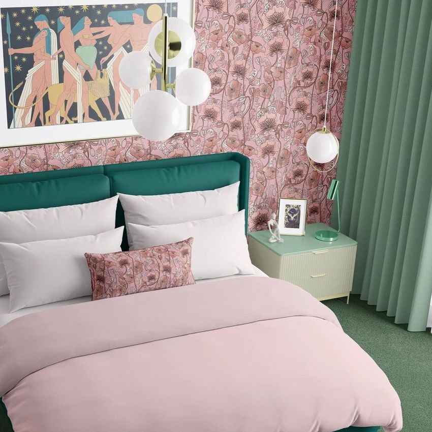 Bedroom scene bedding mockup showing a neatly made bed with pink and white linens, patterned pillow, and floral wallpaper.
