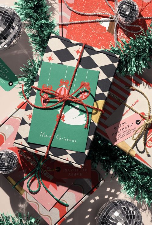 Christmas-themed mockup featuring wrapped presents with colorful patterns, disco ball ornaments, and green tinsel.