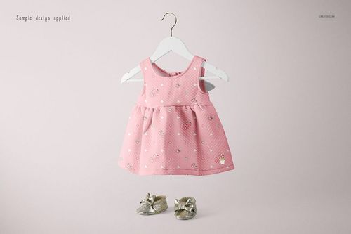 Pink baby dress mockup displayed on a hanger, featuring a soft pattern and paired with metallic gold baby shoes.