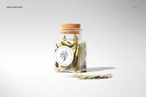 Mockup of a clear spice jar with cork stopper, round label on front, filled with dried leaves, minimalist setting.