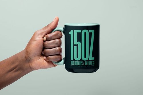 PSD mockup showing a person gripping a black ceramic mug with mint green details and prominent typography design.