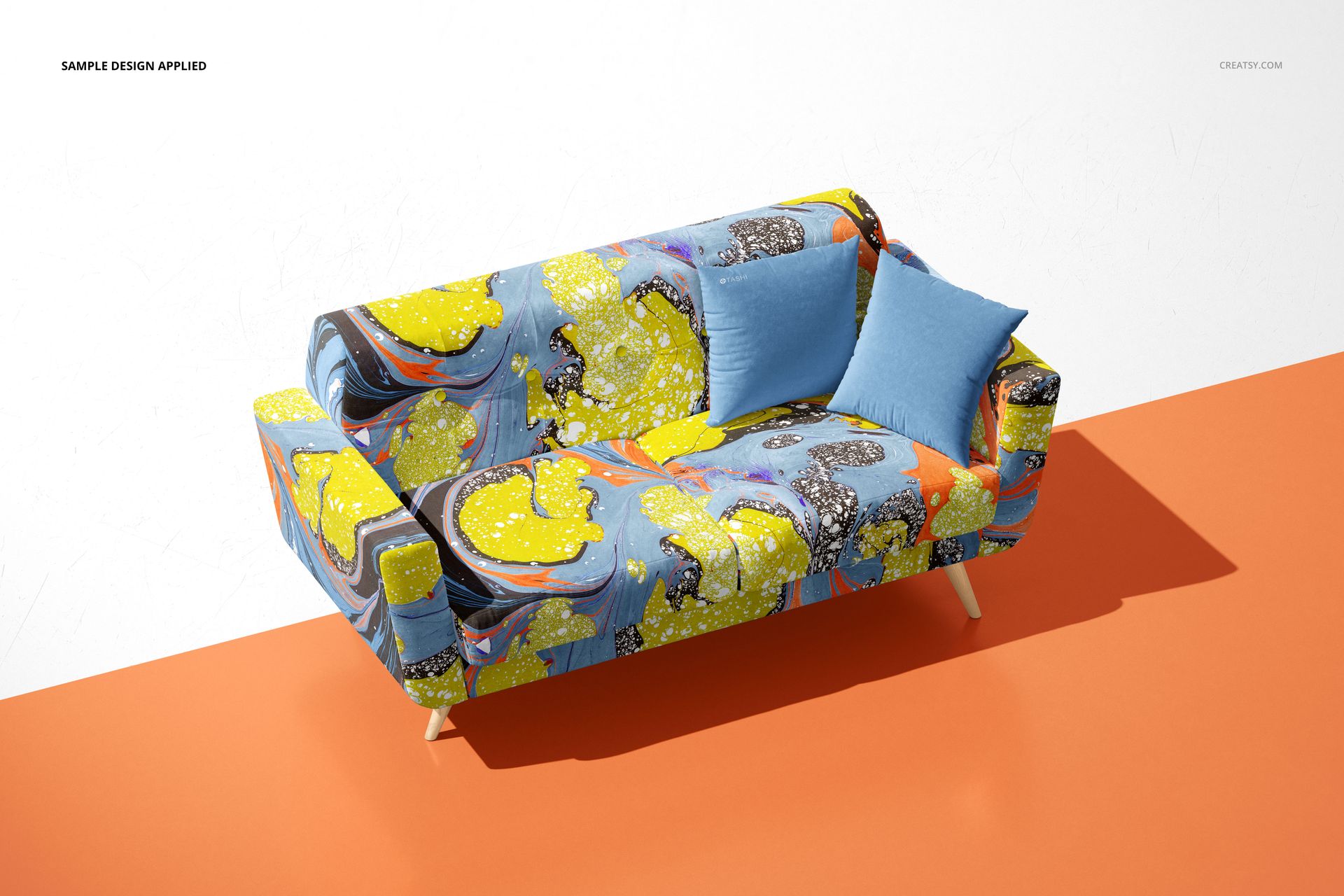 PSD mockup of a contemporary sofa featuring abstract marbled upholstery and two solid blue pillows, angled view.
